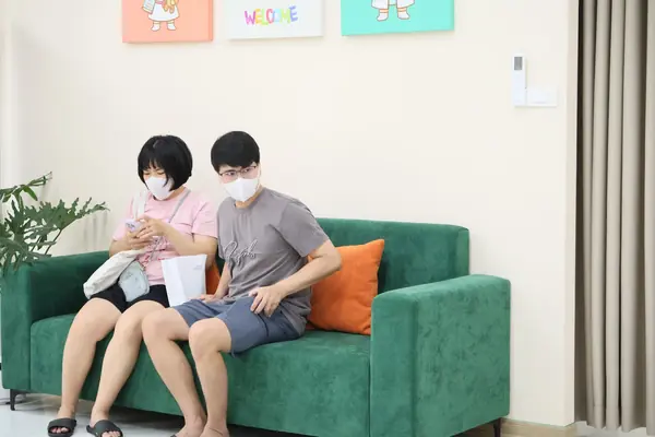 Phụ huynh và bé ngồi chờ khám tại sofa phòng khám